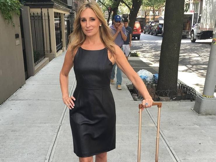 sonja morgan indossa un vestito di pelle nera con una valigia mentre camminando per la strada di New York